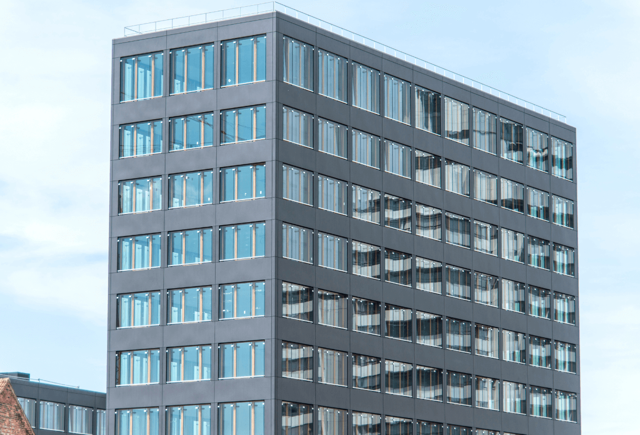 The image shows a large medical building with lots of windows on all sides, and there's a beautiful blue sky in the background.